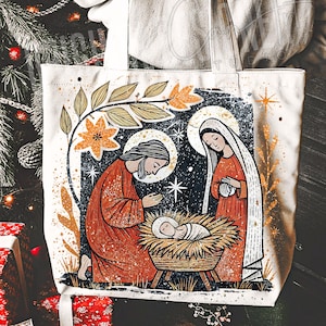 May include: Off-white tote bag featuring a nativity scene illustration. The design includes figures in orange robes, a baby in a manger, and floral accents. The artwork has a vintage, distressed style, with a starry night background.