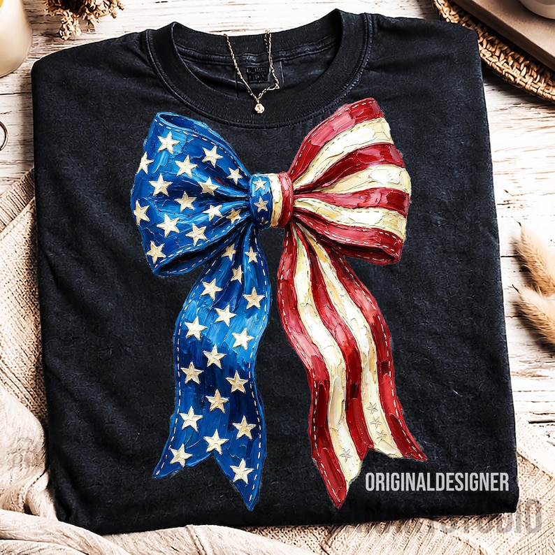 May include: Black t-shirt with a large bow design in patriotic colours. The bow features blue and white stars on one side and red and white stripes on the other. The text "ORIGINALDESIGNER" is at the bottom.