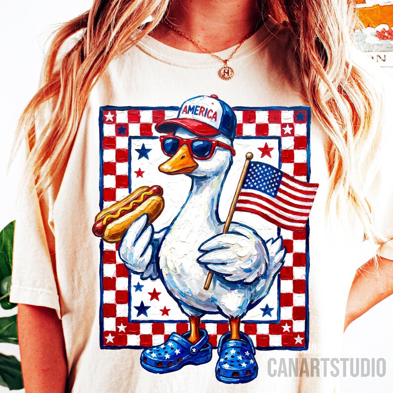 May include: Cream-colored t-shirt featuring a patriotic goose wearing sunglasses, a hat that says "AMERICA", and blue star-patterned shoes. The goose holds a hot dog and an American flag. The background has a red, white, and blue checkered pattern.