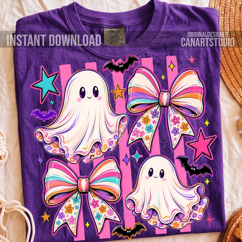 May include: A purple t-shirt featuring a graphic print of two white ghosts, two large multi-colored bows with floral patterns, several small black bats, and various pink, orange, and teal stars against a background of vertical pink stripes.