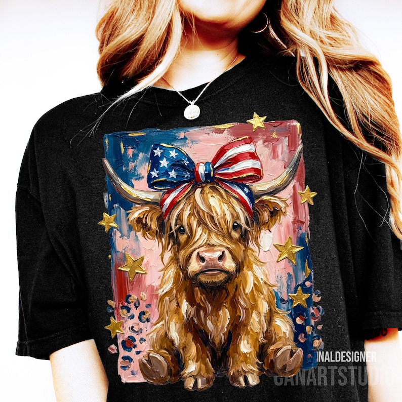 Peut inclure: T-shirt noir avec une illustration de vache des Highlands orn&eacute;e d'un n&oelig;ud patriotique et d'&eacute;toiles dor&eacute;es. La vache a de longs poils bruns et hirsutes, sur un fond de coups de pinceau rouges, blancs et bleus. Th&egrave;me patriotique.