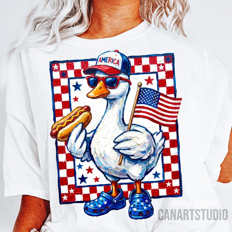 May include: White t-shirt featuring a patriotic goose wearing sunglasses, a baseball cap with "AMERICA" on it, and blue clogs. The goose holds a hot dog and an American flag. The design includes a red, white, and blue checkered border with stars.