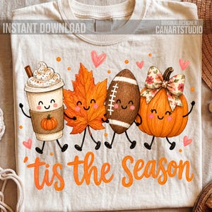 May include: A cream-colored t-shirt featuring a graphic of a coffee cup, an orange maple leaf, a brown football, and an orange pumpkin, all with smiling faces. The text 'tis the season' is printed in orange below the characters with small hearts.