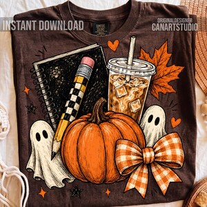 May include: A dark brown t-shirt featuring a graphic print of a spiral notebook, a yellow pencil, an iced coffee cup, a large orange pumpkin, two white ghosts, and an orange plaid bow, accented with orange maple leaves and small stars.