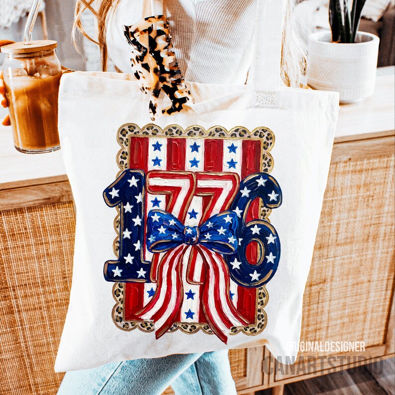 May include: White tote bag featuring a patriotic design with the number "1776" in blue and red, accented with white stars and a blue bow. The design is framed with a leopard print border, perfect for carrying essentials.
