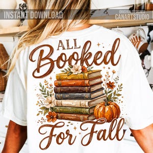 May include: White t-shirt with a fall-themed graphic. The design features a stack of books, a pumpkin, and floral accents. Text reads "All Booked For Fall" in brown script. "Instant Download" and "CanArtStudio" are also visible.