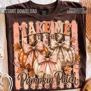 May include: A dark brown t-shirt featuring a graphic of three pumpkins with bows, surrounded by autumn leaves and the text "TAKE ME TO THE PUMPKIN PATCH". The design includes vertical stripes in shades of pink and white, with small hearts and stars.