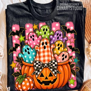 May include: A dark gray t-shirt featuring a graphic of a large orange jack-o'-lantern with a black and white checkered bow, filled with colorful polka-dot ghosts. The design includes black bats, green and yellow stars, and pink stripes.