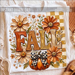 May include: White t-shirt featuring a fall-themed design. The design includes the word "FALL" in textured letters, surrounded by orange and cream-colored flowers, a pumpkin with a checkered bow, and the text "INSTANT DOWNLOAD".