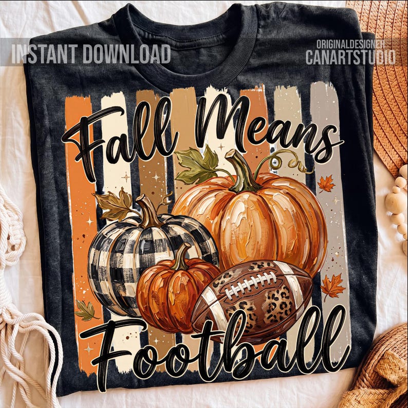 May include: Black t-shirt with a fall-themed graphic. The design features pumpkins, a football with a leopard print, and the text "Fall Means Football" in a decorative font. The background includes vertical stripes in orange, brown, and beige.