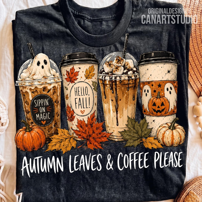 May include: A black t-shirt featuring a graphic of four coffee cups decorated with autumn themes, including ghosts, pumpkins, and maple leaves. The text reads Sippin' on Magic, Hello, Fall!, and Autumn Leaves & Coffee Please in white lettering.