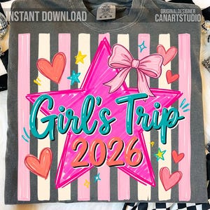 May include: Dark gray sweatshirt with a pink star and bow graphic. The design includes the text "Girl's Trip 2026" in teal and orange, along with pink hearts and stars. The shirt has vertical pink and white stripes.