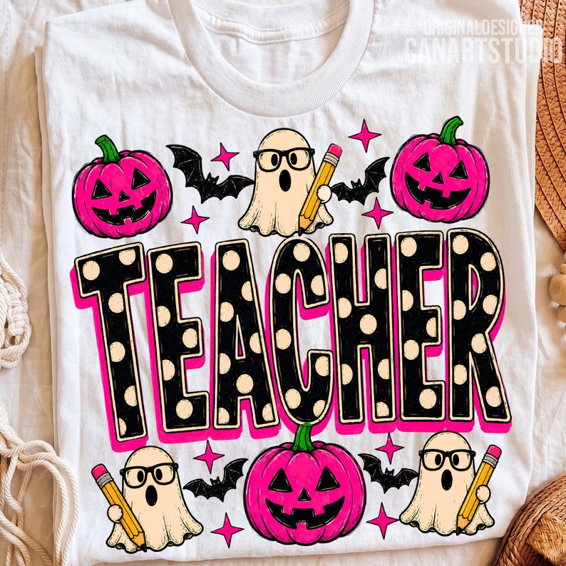 May include: A white t-shirt featuring a graphic print with the word TEACHER in large black letters with white polka dots. The design includes three pink jack-o'-lanterns, three ghosts wearing black glasses and holding yellow pencils, and black bats.