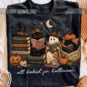 May include: A dark gray t-shirt featuring a graphic of a black cat wearing a witch hat reading a book, a ghost in a witch hat reading a book, and a black cat sleeping on a book. The design includes pumpkins, a crescent moon, and the text all booked for halloween.