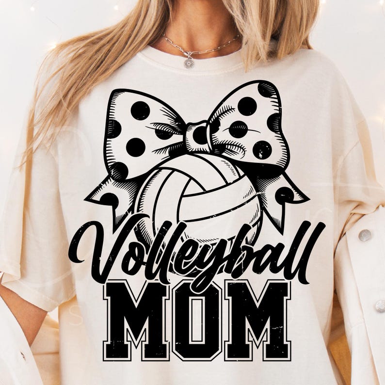 May include: White t-shirt with a black and white graphic of a volleyball with a polka dot bow and the text "Volleyball Mom".