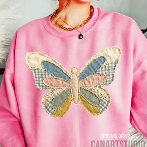 May include: Pink sweatshirt featuring a patchwork butterfly design. The butterfly has wings in various colors and patterns, including blue gingham, floral, and solid fabrics. The text "ORIGINALDESIGNER CANARTSTUDIO" is printed on the bottom right.
