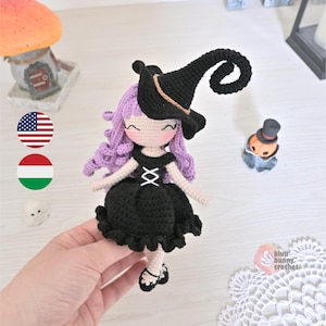 May include: Crocheted witch doll with purple hair, a black dress, and a black witch hat. The doll is holding a broom and is wearing black shoes.