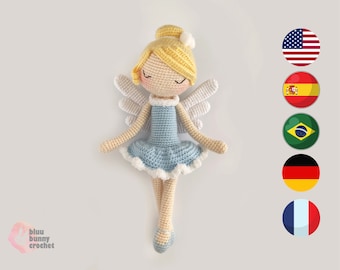 Puede incluir: Una muñeca de ángel de crochet con cabello rubio, vestido azul y alas blancas. La muñeca lleva zapatos de ballet blancos y tiene una flor blanca en la cabeza.