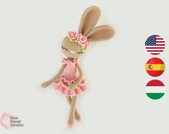 May include: A crocheted ballerina bunny with pink dress and a flower crown. The bunny is brown and has long ears. The bunny is lying on its side with its legs extended.