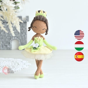 May include: Crocheted doll in a princess design. The doll has brown hair, a green crown, and a yellow and green dress with a white tulle skirt. The doll's arms and feet are green. The doll is standing on a white surface.
