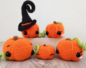 May include: Five crocheted pumpkins, one wearing a black witch hat, with green stems and black eyes.