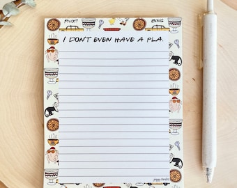 May include: A white notepad with a Friends TV show theme. The notepad has a yellow background with black outlines of various characters and objects from the show. The text "I don't even have a pla." is written in black at the top of the notepad.