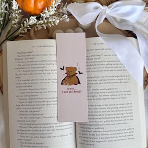 May include: A bookmark with a teddy bear in a vampire cape, the text "BEWARE... I READ PAST MIDNIGHT", and bats. The bookmark is placed in an open book with text.