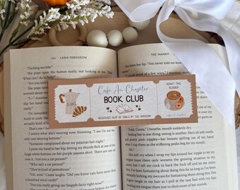 May include: An open book with text, a decorative bookmark, and two pumpkins. The bookmark reads "Cafe Au Chapter Book Club" with coffee and croissant illustrations. A white ribbon and decorative white balls are also present.