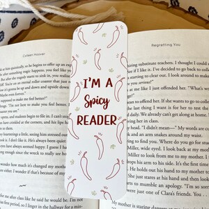 K&ouml;nnte beinhalten: Wei&szlig;es Lesezeichen mit roten Chili-Pfeffer-Illustrationen. Das Lesezeichen tr&auml;gt den Text "I'm a Spicy Reader" in brauner Schrift.