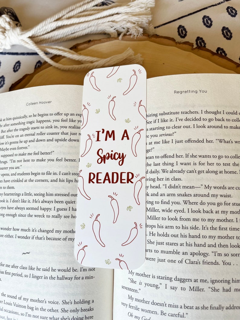 K&ouml;nnte beinhalten: Wei&szlig;es Lesezeichen mit roten Chili-Pfeffer-Illustrationen. Das Lesezeichen tr&auml;gt den Text "I'm a Spicy Reader" in brauner Schrift.