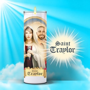 May include: A white candle with a picture of a woman and a man on it. The woman is holding a microphone and the man is smiling. The candle has the words "Saint Traylor" on it.