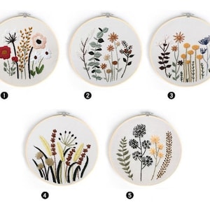 May include: Five embroidery hoops with different floral designs. Each hoop features a variety of flowers and leaves in shades of green, brown, yellow, and red. The hoops are all the same size and are made of wood.