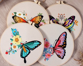 Pode incluir: Quatro aros de bordado com borboletas de diferentes cores e desenhos florais. As borboletas são bordadas em tons de laranja, azul, rosa e roxo.