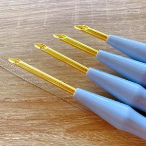 May include: Four blue and gold embroidery needles with a gold eye and a blue plastic handle.