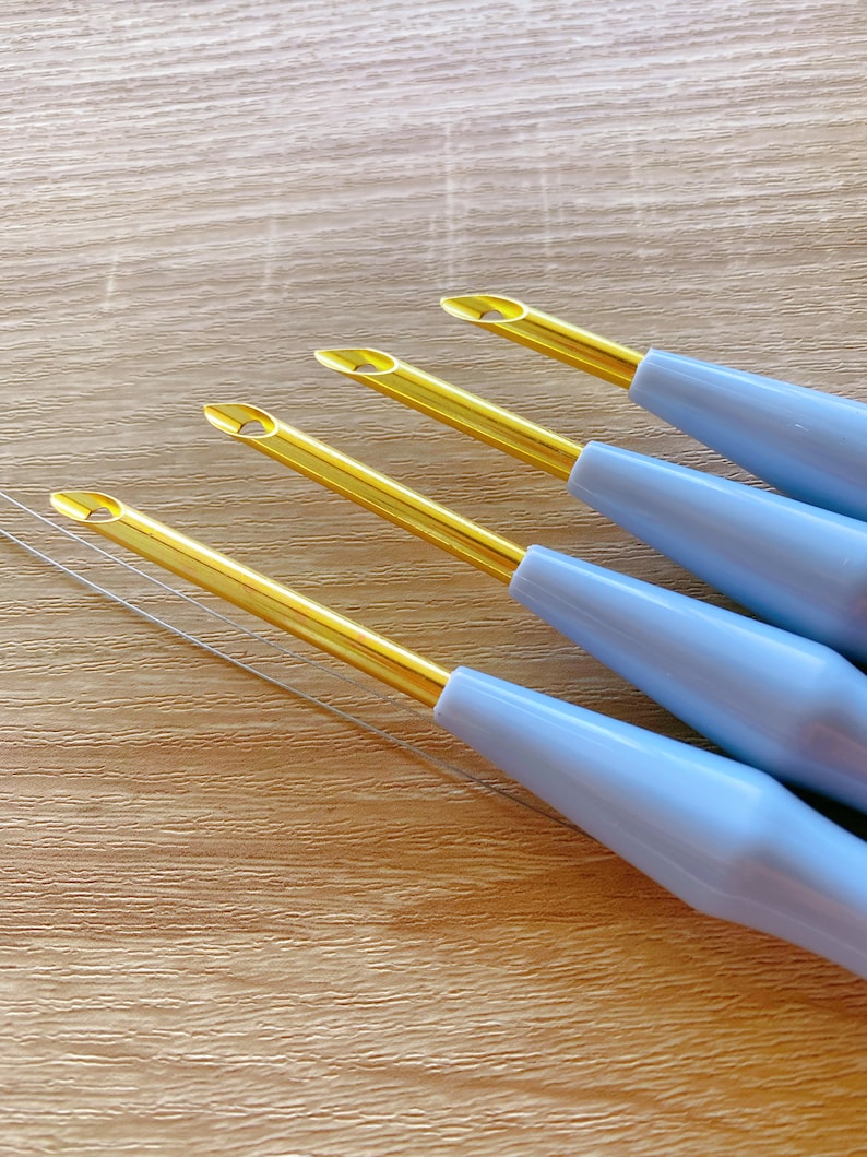 May include: Four blue and gold embroidery needles with a gold eye and a blue plastic handle.