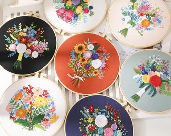 Puede incluir: Seis aros de bordado con diferentes diseños florales. Los aros son de madera y tienen un fondo blanco. Las flores están bordadas en varios colores, incluyendo rosa, amarillo, azul y verde.