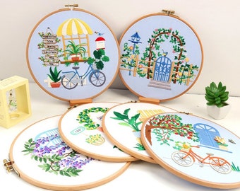 Puede incluir: Seis aros de bordado con diferentes escenas florales y de jardín. Las escenas incluyen una bicicleta, una puerta, una casita para pájaros y un árbol. Los aros son de madera y tienen un acabado marrón claro.