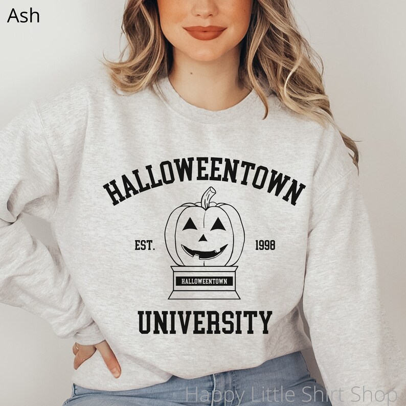 Puede incluir: Una sudadera gris con un estampado gr&aacute;fico negro que dice "Halloweentown University" con una calabaza y el texto "Est. 1998".