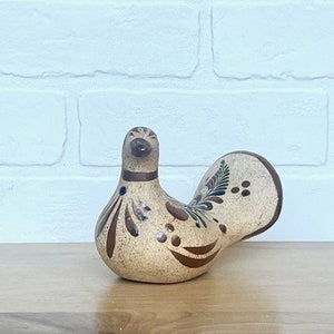 May include: A hand-painted ceramic bird figurine with brown, blue, and white floral designs. The bird has a rounded body and a long tail.