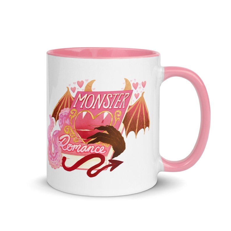 May include: White ceramic mug with a pink interior and handle. The mug features a colorful illustration with the text "MONSTER Romance" on a book with a heart, wings, and a devil's tail.
