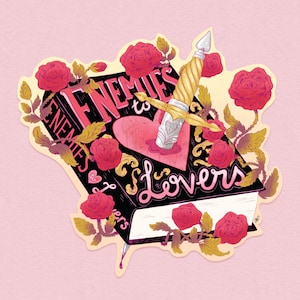 May include: A sticker featuring a book with the words "Enemies to Lovers" and a dagger piercing a heart. Red roses and gold leaves surround the book. The background is a soft pink.