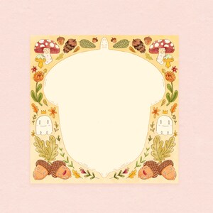 May include: Watercolor illustration of a cream-colored acorn shape with a decorative border. The border features mushrooms, acorns, leaves, flowers, and smiling ghost characters. The background is a light pink.