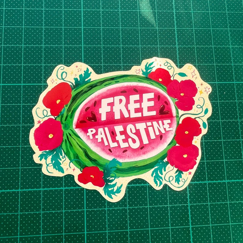 Peut inclure: Un autocollant avec un motif de past&egrave;que et les mots "FREE PALESTINE" en blanc. La past&egrave;que est entour&eacute;e de coquelicots rouges et de feuilles vertes, sur une bordure cr&egrave;me.