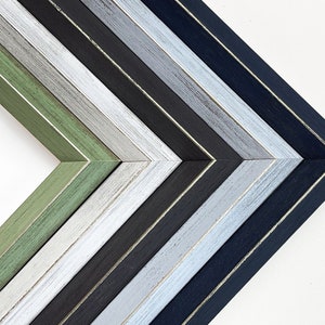 May include: A set of eight picture frames with different colored wood finishes. The frames are arranged in a staggered pattern, with the darkest frame at the bottom and the lightest frame at the top. The frames are all made of wood and have a simple, classic design.