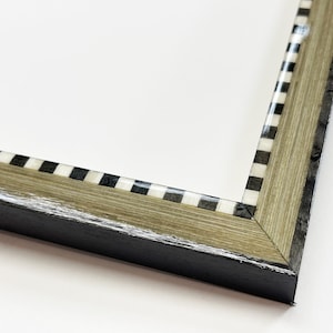 May include: Close-up of a picture frame with a black and white checkered border. The frame is made of wood with a light brown stain and a black outer edge.