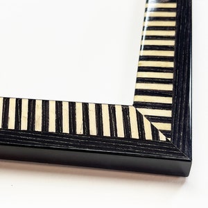 May include: Black picture frame with a white and black striped border.