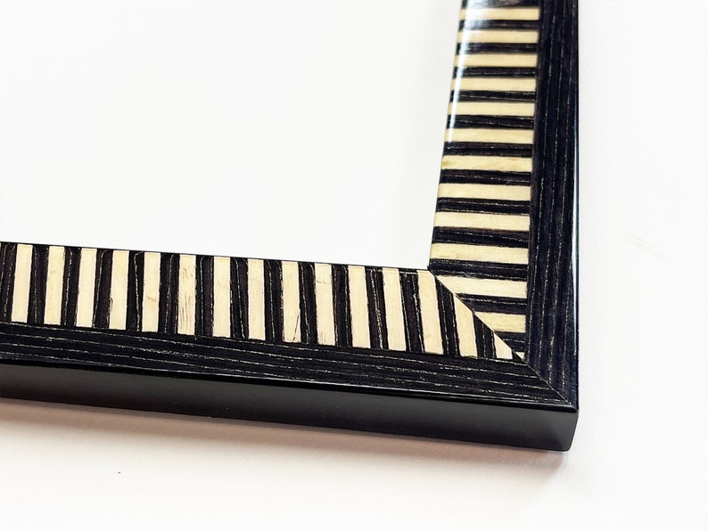 May include: Black picture frame with a white and black striped border.