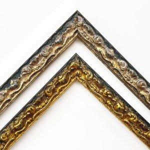 May include: Two ornate picture frames with gold and silver leaf accents. The frames have a black background and a decorative, swirling design.