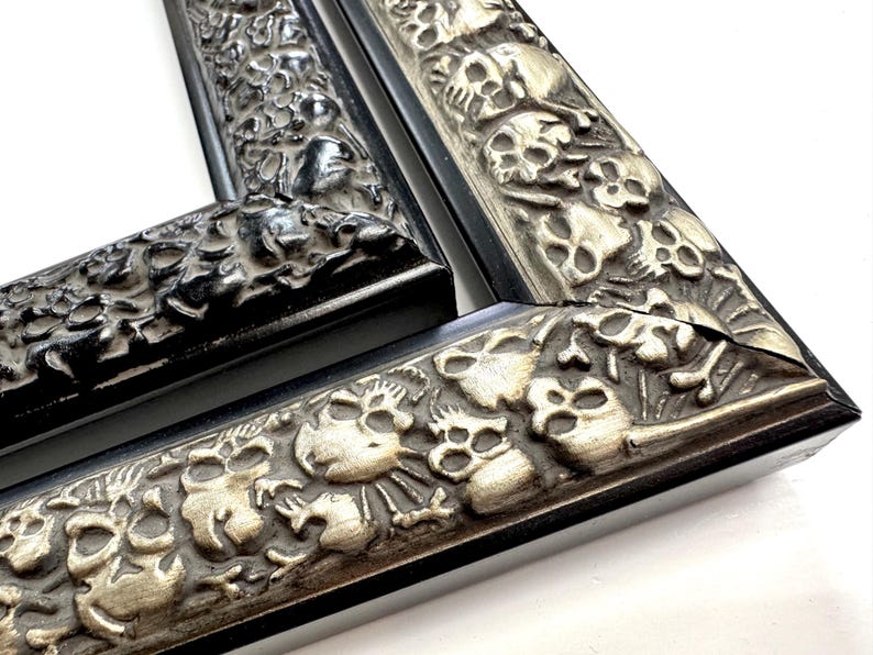 May include: Two black picture frames with ornate silver skull designs. The frames are made of wood and have a black finish. The skull designs are raised and detailed. Skulls Gothic Picture Frames Silver Black Eclectic Unique Photo Display Metallic Wood  Gift Wall Deco 4x6 5x7 8x10 11x14 16x20 18x24