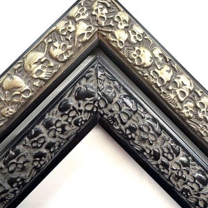 May include: Two picture frames with a skull design. The frame on the left is black with a silver skull design. The frame on the right is gold with a silver skull design. Skulls Gothic Picture Frames Silver Black Eclectic Unique Photo Display Metallic Wood Gift Wall Deco 4x6 5x7 8x10 11x14 16x20 18x24